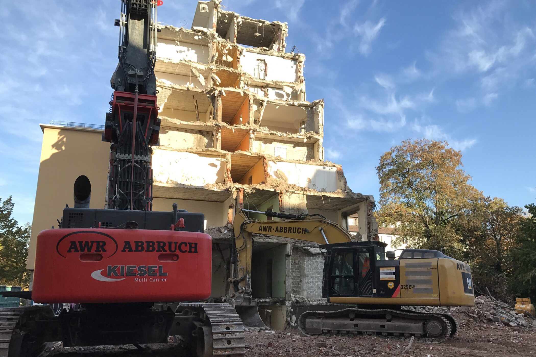 Abriss eines mehrstöckigen Gebäudes mit zwei Baggern im Vordergrund.