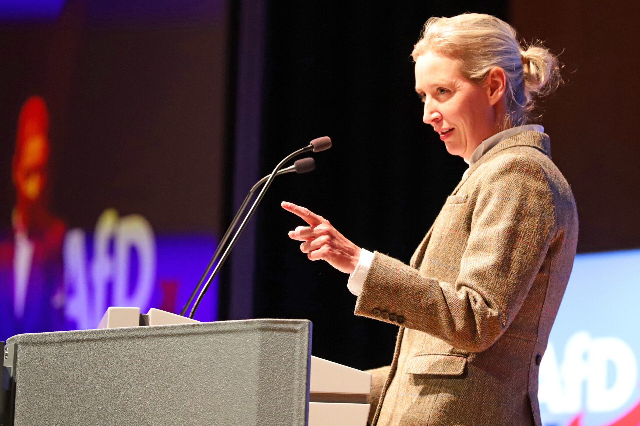 Eine Frau spricht an einem Rednerpult mit Mikrofonen.
