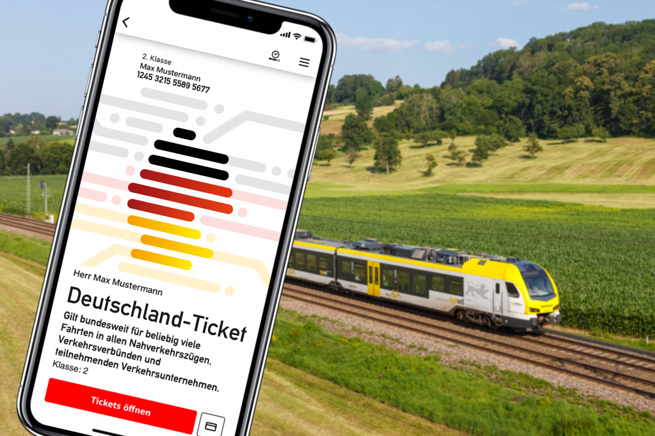 Smartphone mit Deutschland-Ticket-App, Zug im Hintergrund auf Gleisen, grüne Landschaft.