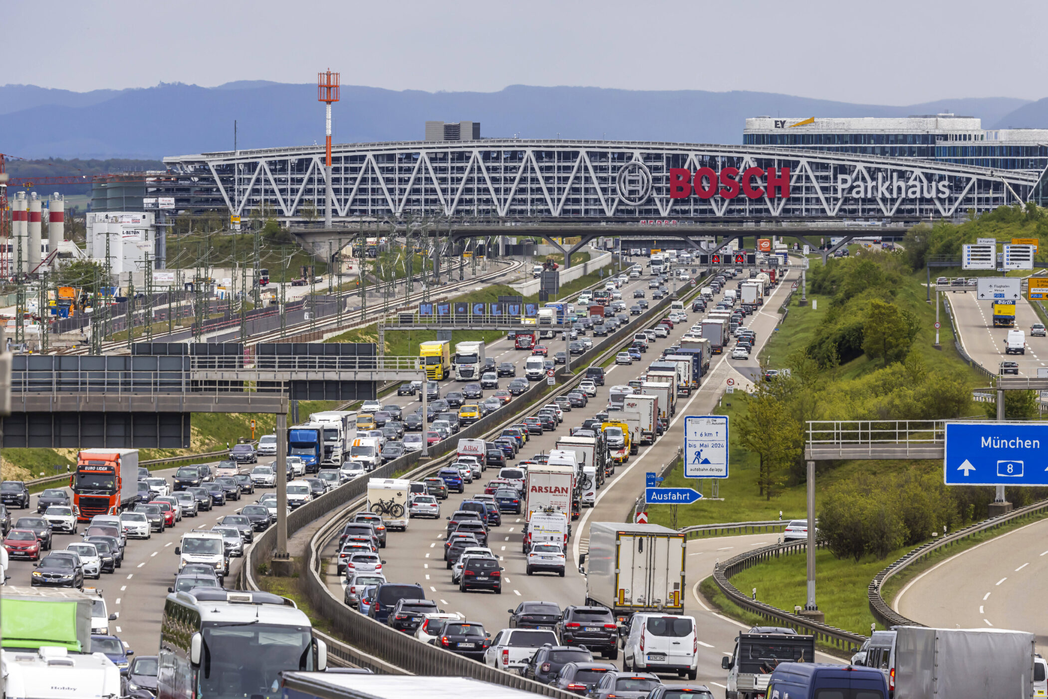 Autobahn mit dichtem Verkehr, Parkhaus im Hintergrund, Schilder Richtung München.