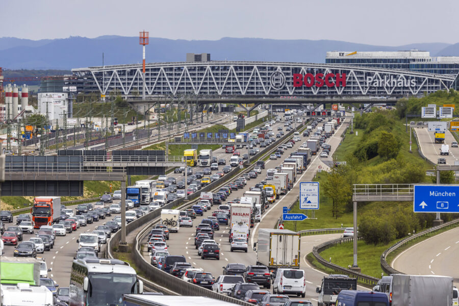 Autobahn mit dichtem Verkehr, Parkhaus im Hintergrund, Schilder Richtung München.