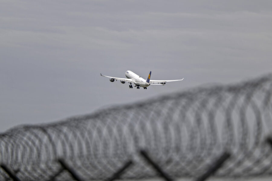Flugzeug hebt ab, im Vordergrund Stacheldrahtzaun.