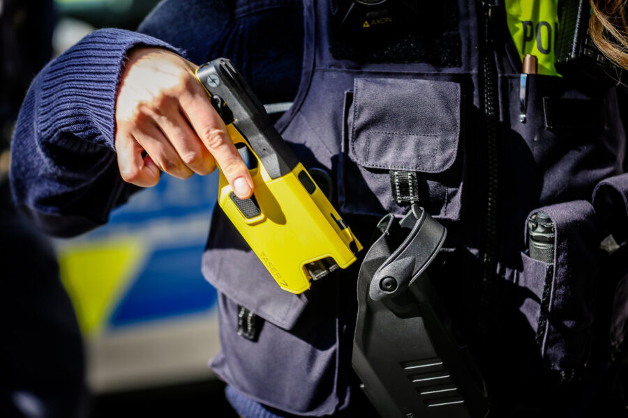 Person in Uniform hält gelbes Gerät mit der Aufschrift "TASER 7".