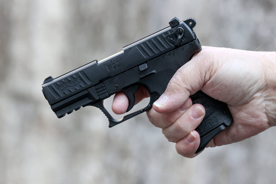 Hand hält eine schwarze Pistole mit der Aufschrift "Walther P22".