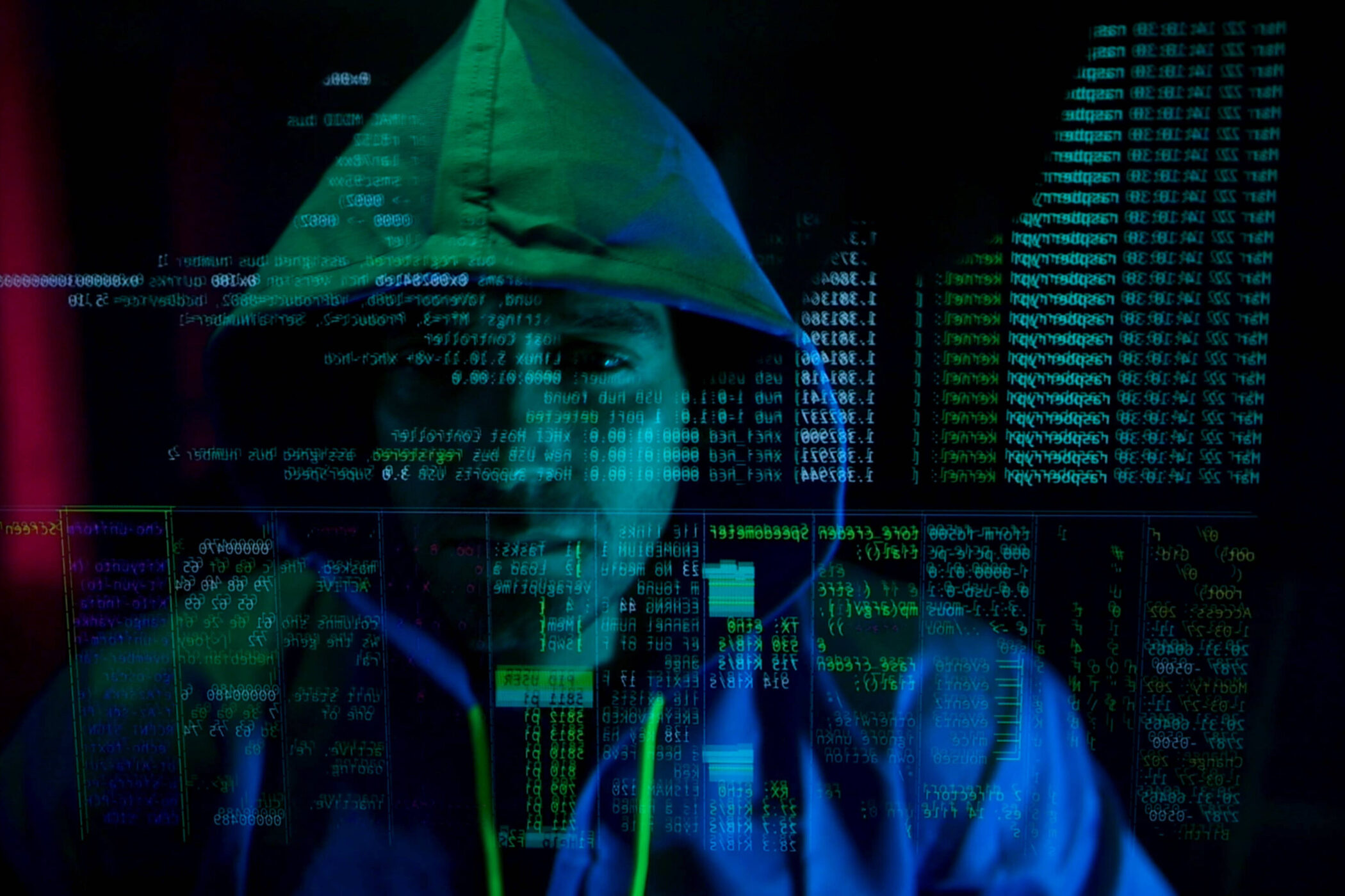 Person mit Kapuze, umgeben von digitalem Code auf einem Bildschirm.