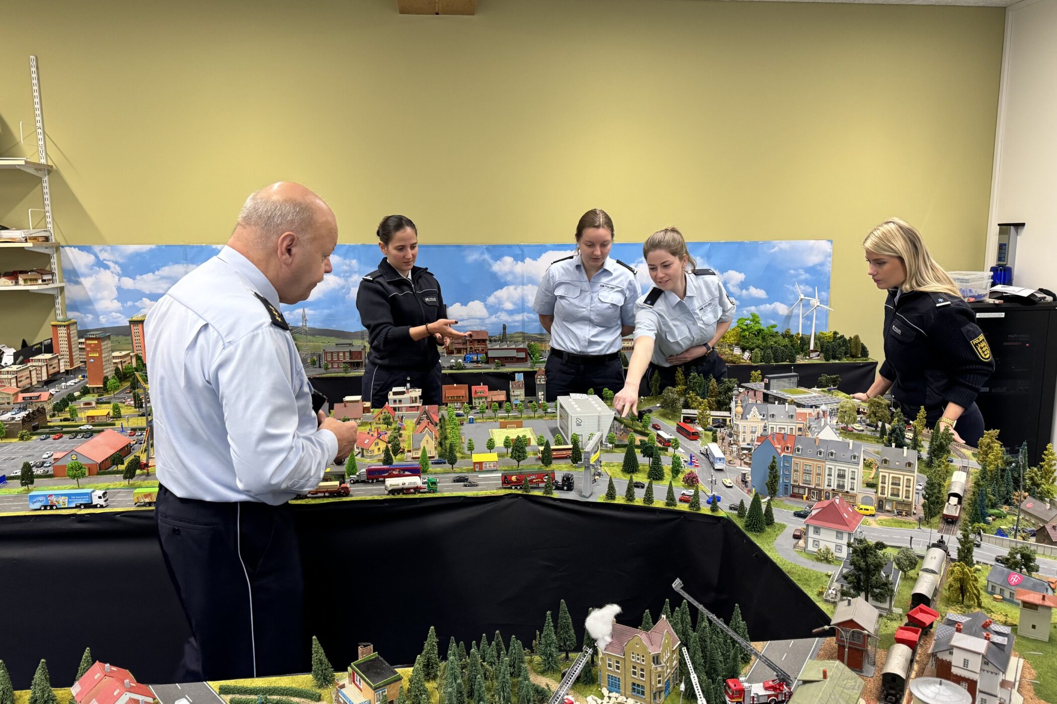 Fünf Personen in Uniform betrachten ein großes Modell einer Stadtlandschaft.