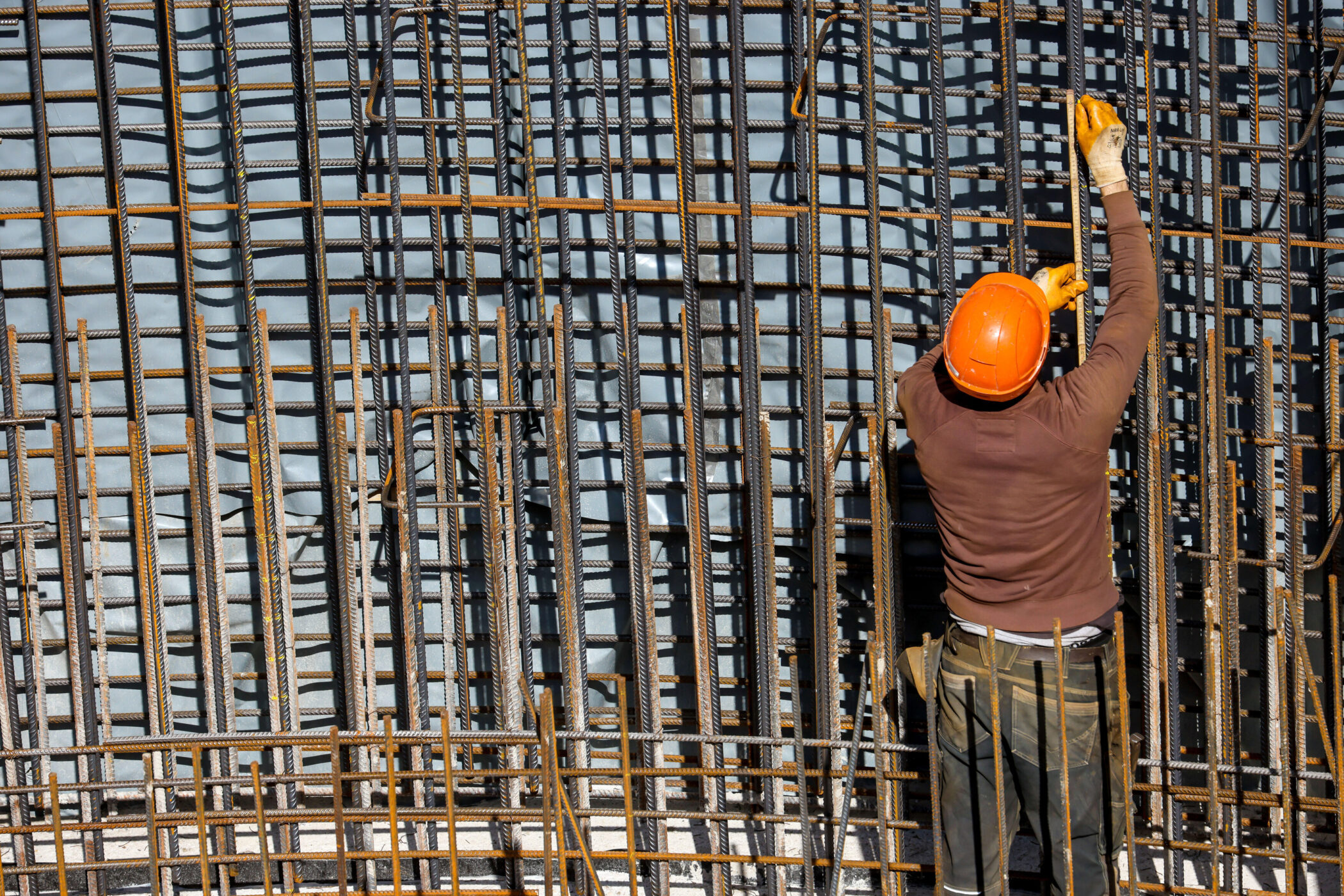 Person mit Helm arbeitet an Stahlverstrebungen.