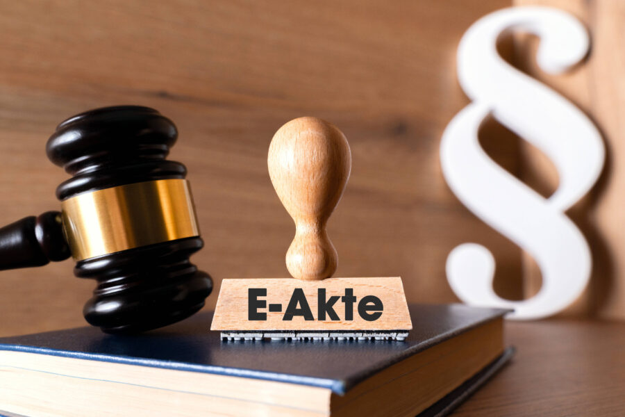 Richterhammer, Stempel mit "E-Akte", Paragraphensymbol im Hintergrund.