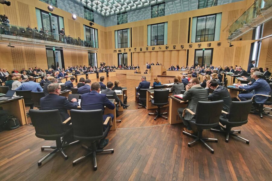 Viele Menschen in einem großen Sitzungssaal mit Holzverkleidung.