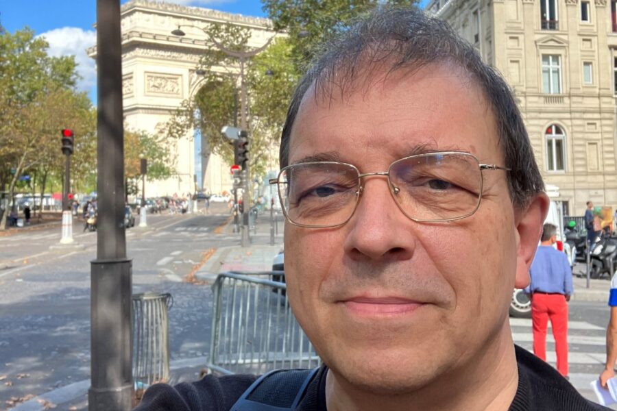 Mann mit Brille vor dem Arc de Triomphe in Paris.