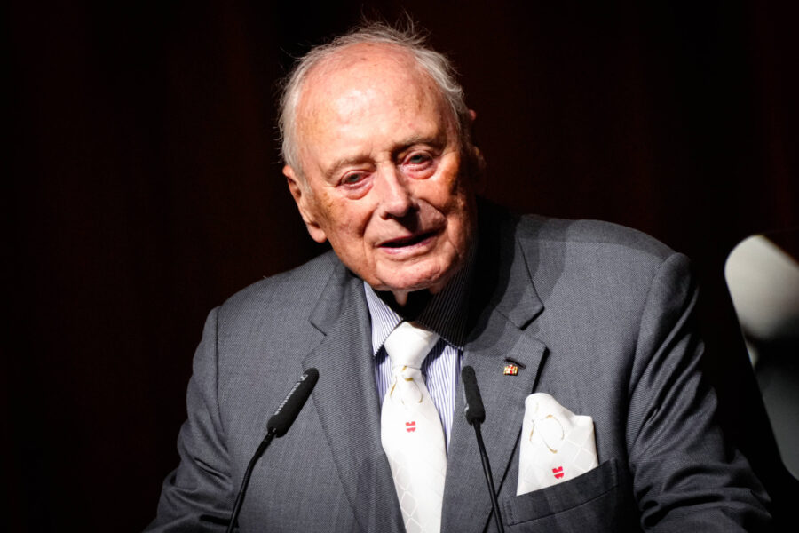 Älterer Mann in Anzug spricht in Mikrofon.