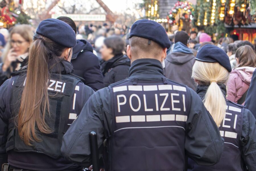 Drei Polizisten in Uniform auf einem belebten Markt.