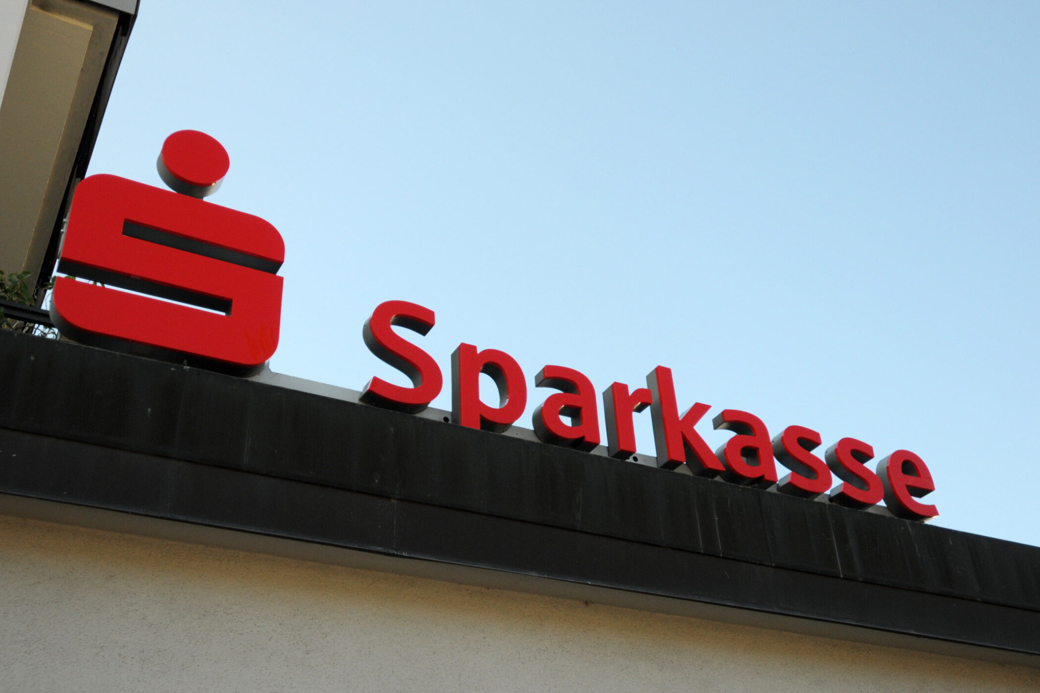 Rotes Sparkasse-Logo und Schriftzug auf Gebäudedach.