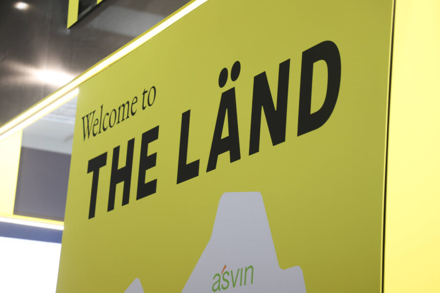 Gelbes Schild mit Text: "Welcome to THE LÄND", darunter "asvin".