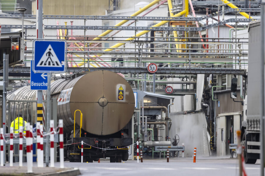 Industriegelände mit Kesselwagen, Rohren und Verkehrsschildern.