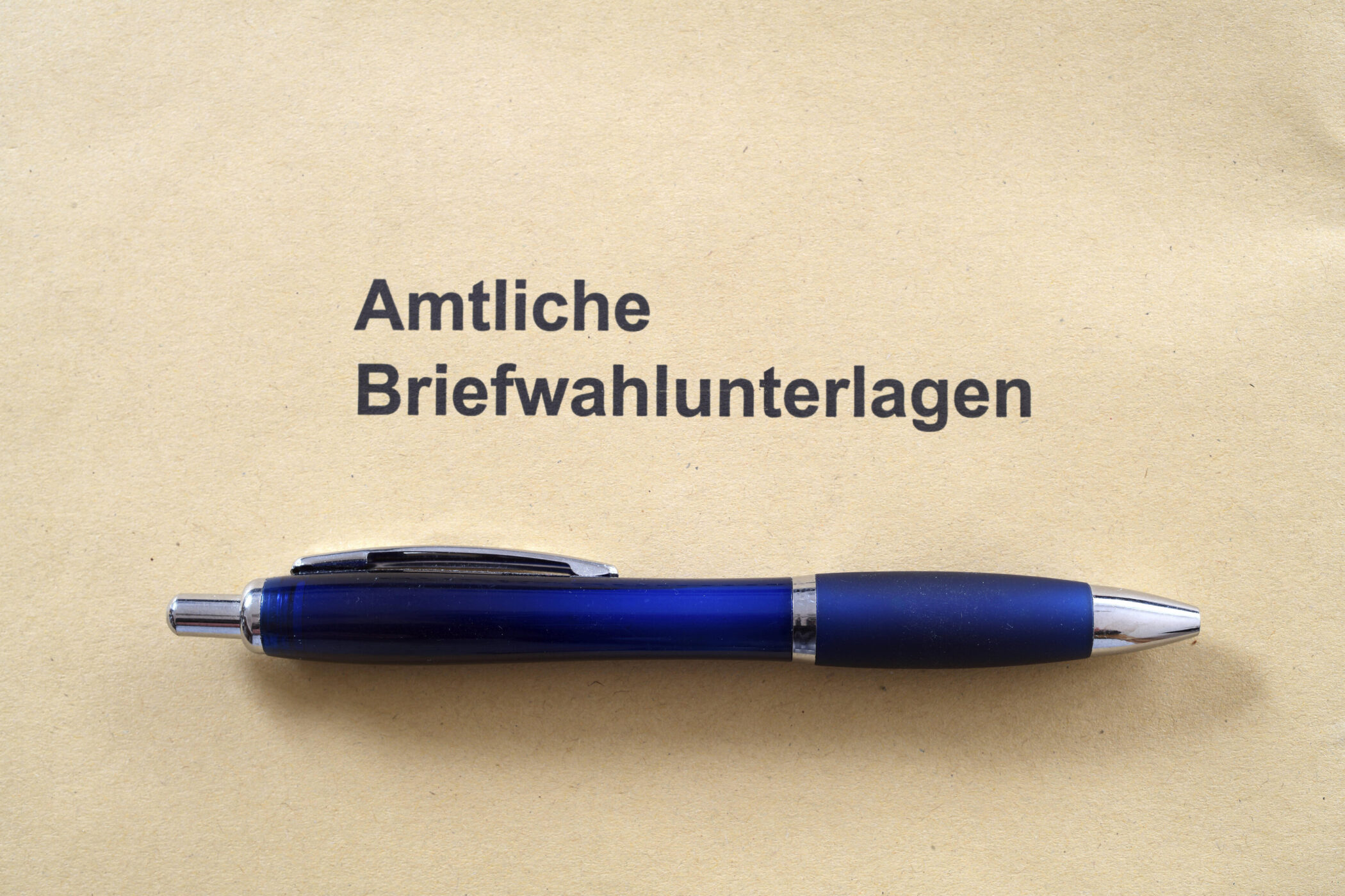 Umschlag mit Aufschrift "Amtliche Briefwahlunterlagen", blauer Kugelschreiber darauf.