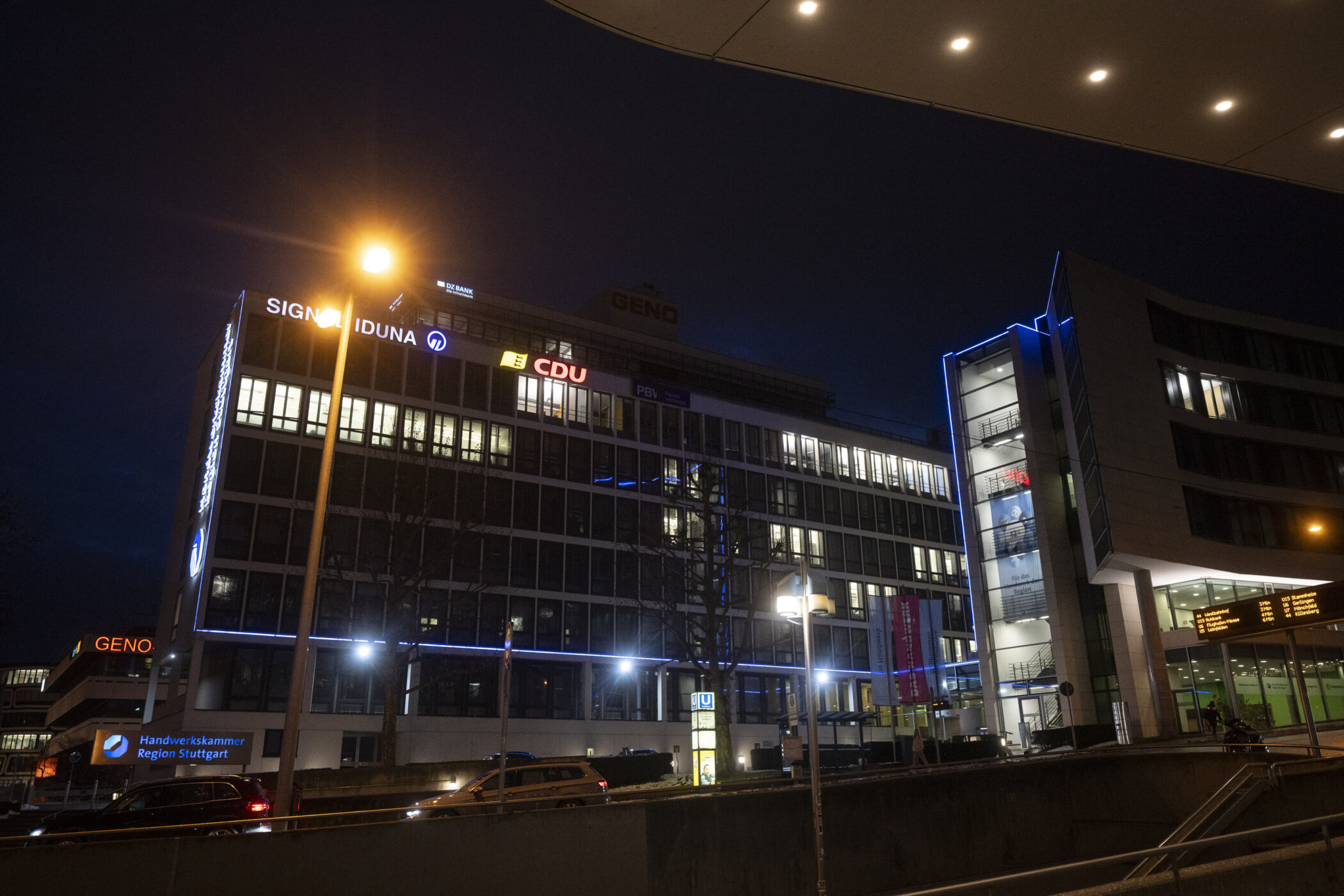 Beleuchtetes Bürogebäude bei Nacht, Schilder von Signal Iduna und CDU sichtbar.