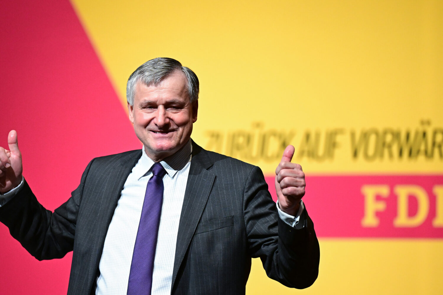 Mann im Anzug zeigt Daumen hoch, Hintergrund mit FDP-Logo und Text "Zurück auf Vorwärts".