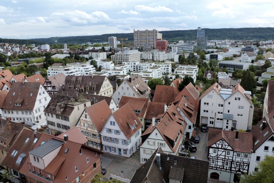 Stadtansicht mit Fachwerkhäusern und modernen Gebäuden im Hintergrund.
