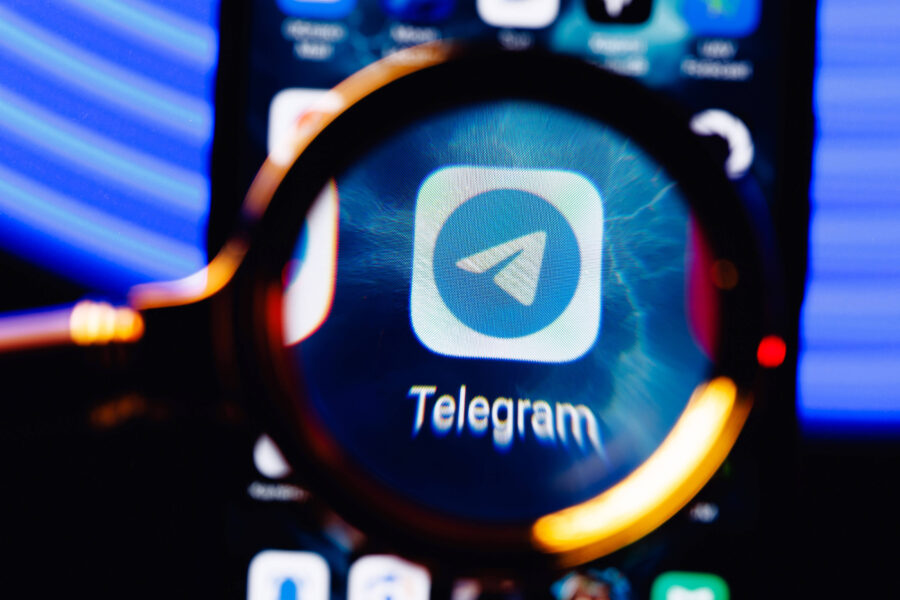 Lupe vergrößert Telegram-App-Logo auf einem Smartphone-Bildschirm.