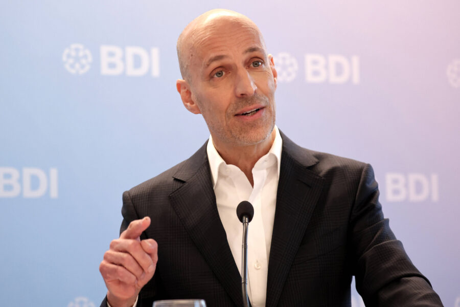 Ein Mann im Anzug spricht in ein Mikrofon, Hintergrund mit "BDI"-Logo.