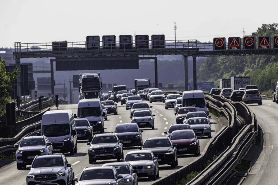 Mehrspurige Autobahn mit dichtem Verkehr und Geschwindigkeitsbegrenzungsschildern.