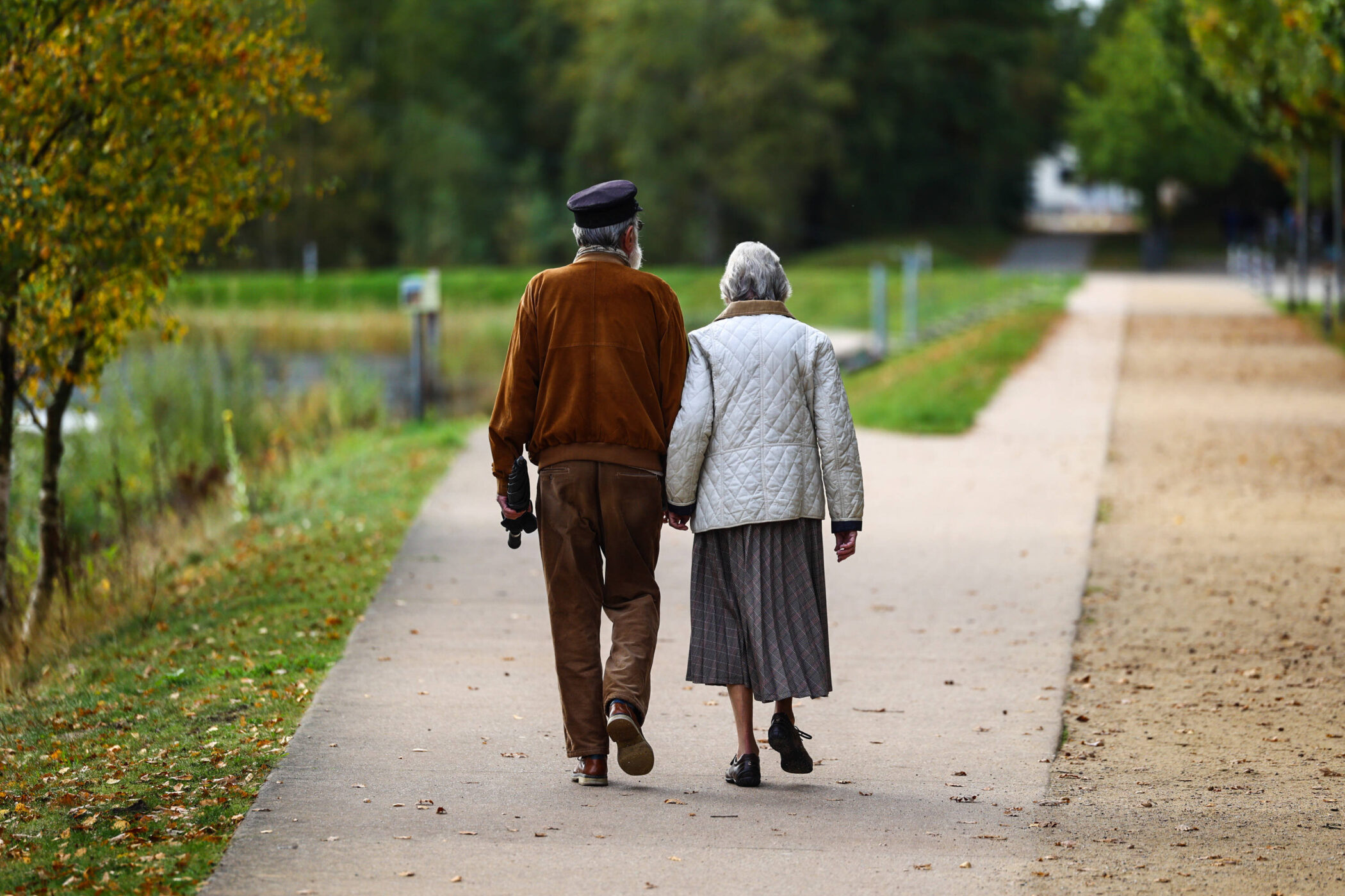 Zwei Personen gehen auf einem Weg im Park spazieren.