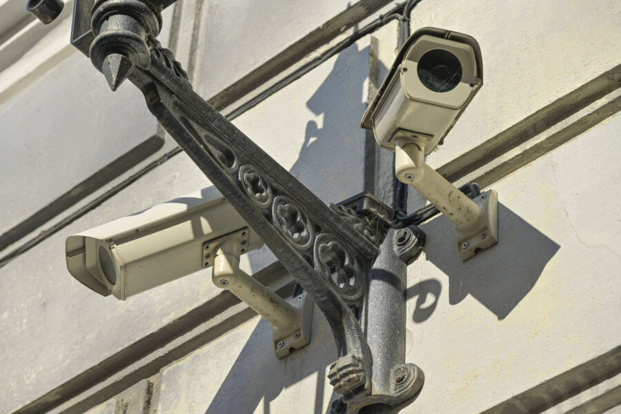 Zwei Überwachungskameras an einer verzierten Wandhalterung.