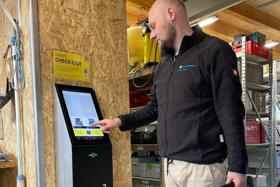 Mann bedient Touchscreen-Terminal in Werkstattumgebung.