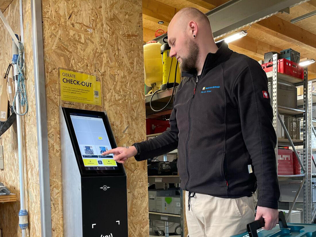 Mann bedient Touchscreen-Terminal in Werkstattumgebung.