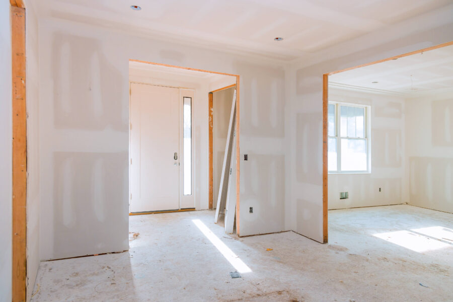 Unfertiger Innenraum mit Trockenbauwänden, Türöffnung und Fenster.