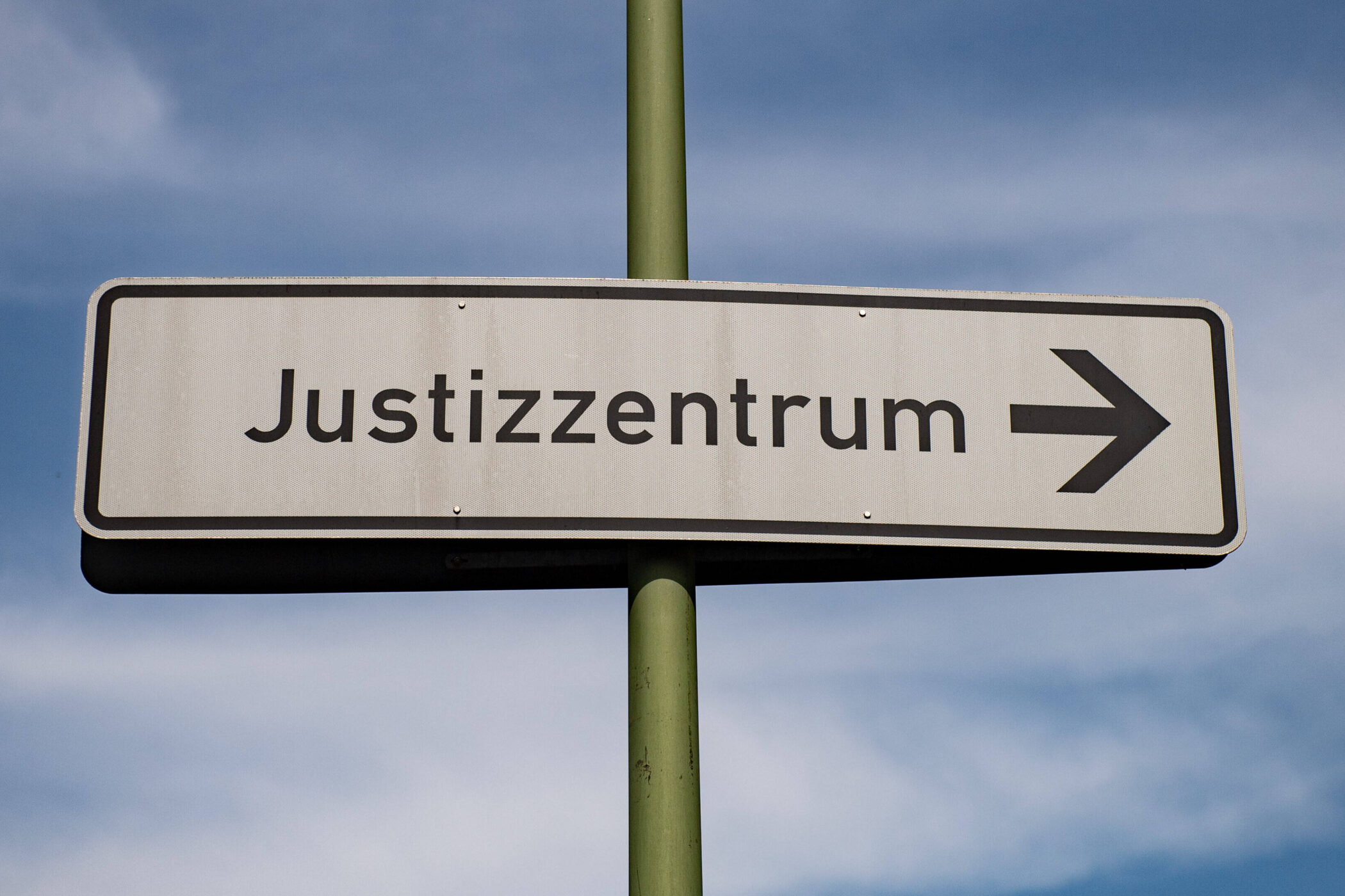 Schild mit Aufschrift "Justizzentrum" und Pfeil nach rechts.