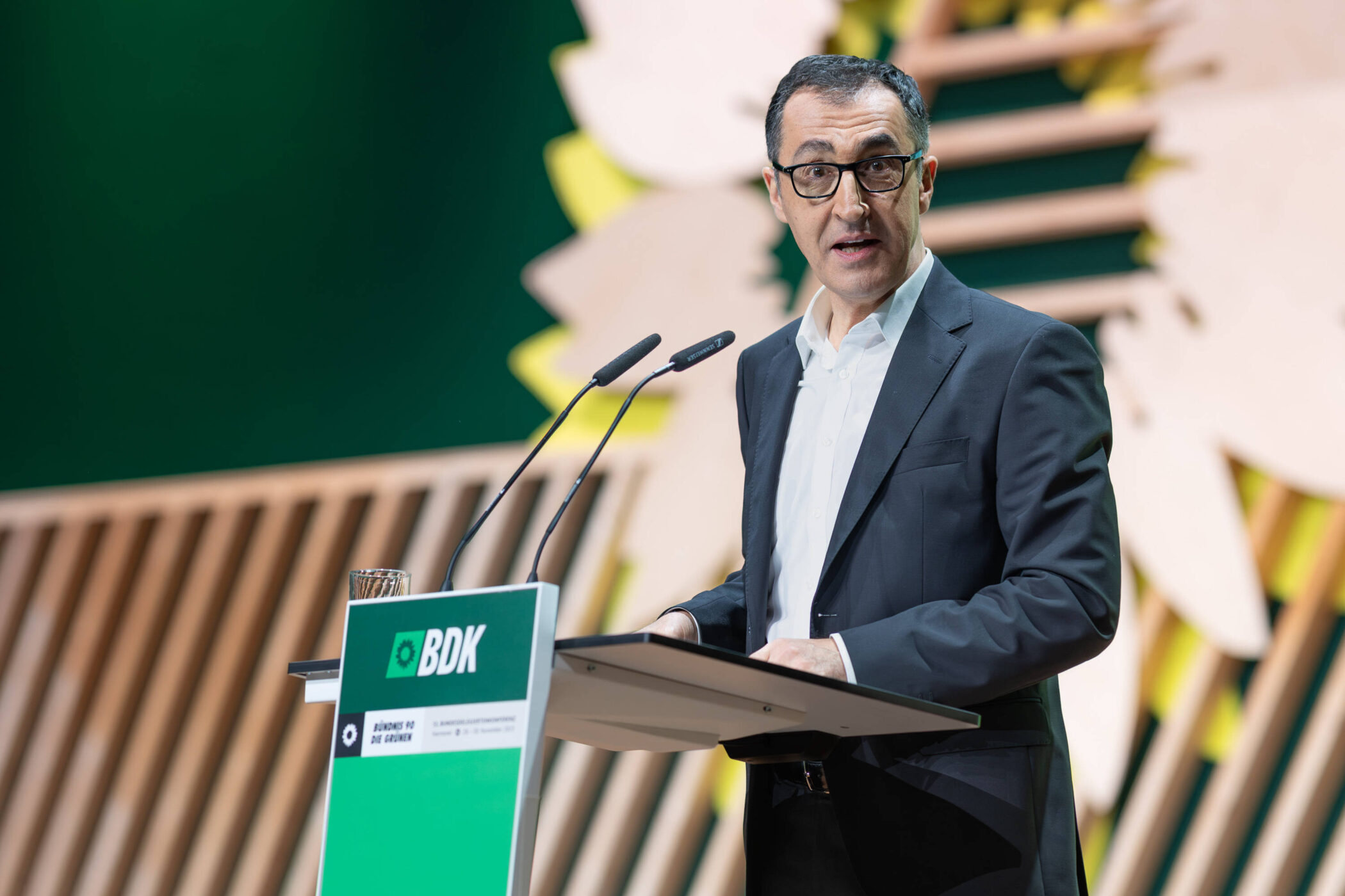 Ein Mann spricht an einem Pult mit grünem BDK-Logo.