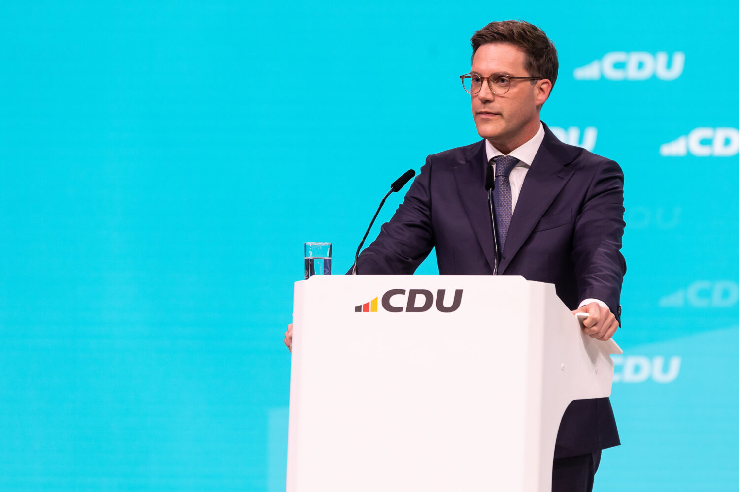 Ein Mann am Rednerpult mit CDU-Logo, hellblauer Hintergrund.