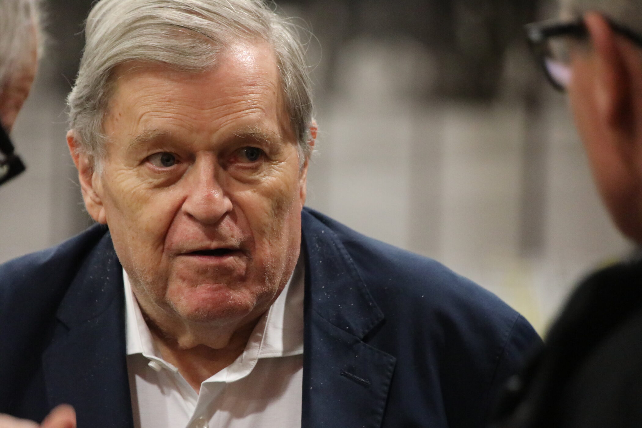 Älterer Mann in Anzug spricht mit zwei Personen.