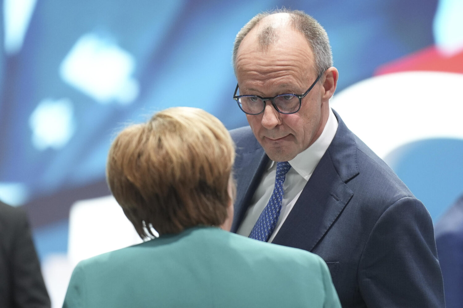 Zwei Personen im Gespräch, eine Frau von hinten, ein Mann mit Brille.