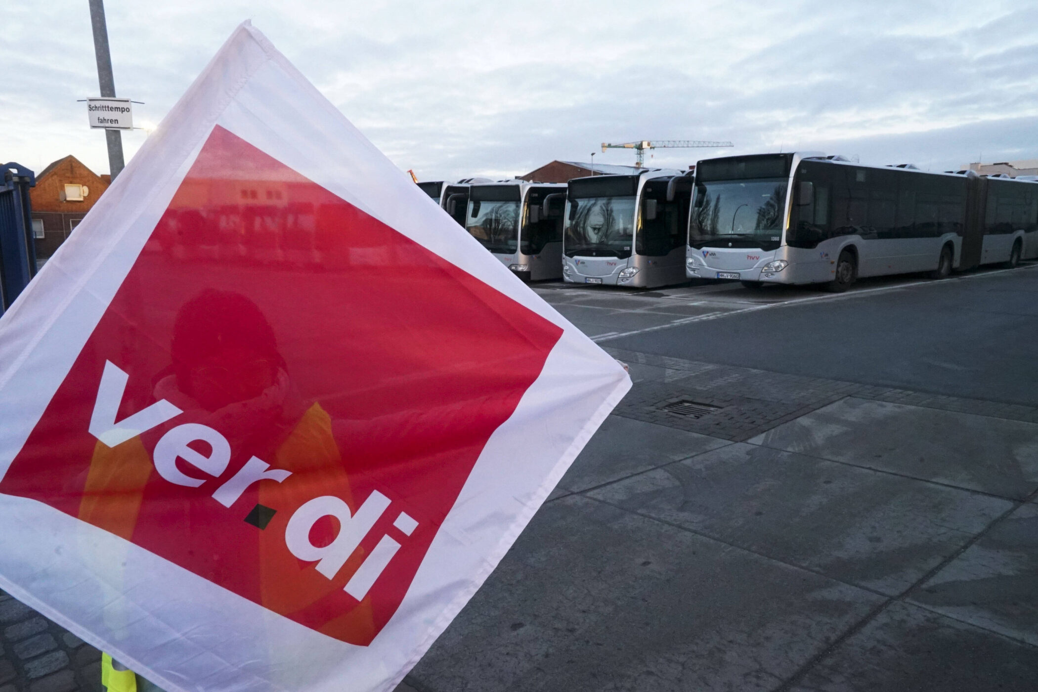Mehrere abgestellte Busse, davor eine Fahne mit „ver.di“-Logo.