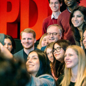 Gruppe von Menschen posiert für ein Selfie vor rotem 