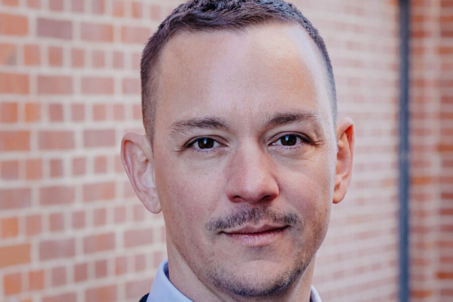 Ein Mann vor einer Backsteinwand.