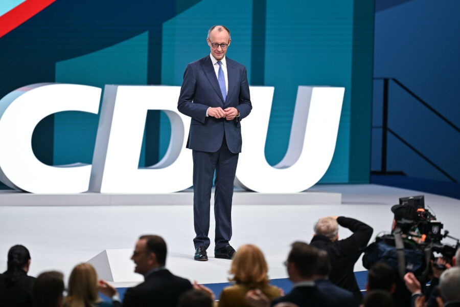 Mann im Anzug auf Bühne mit großem "CDU"-Schriftzug im Hintergrund.