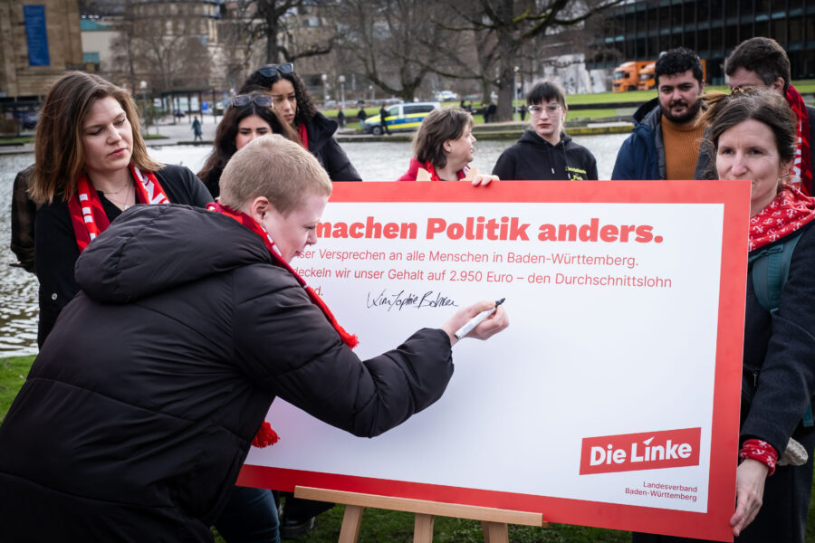 Eine Person unterschreibt ein Plakat mit der Aufschrift "Wir machen Politik anders."