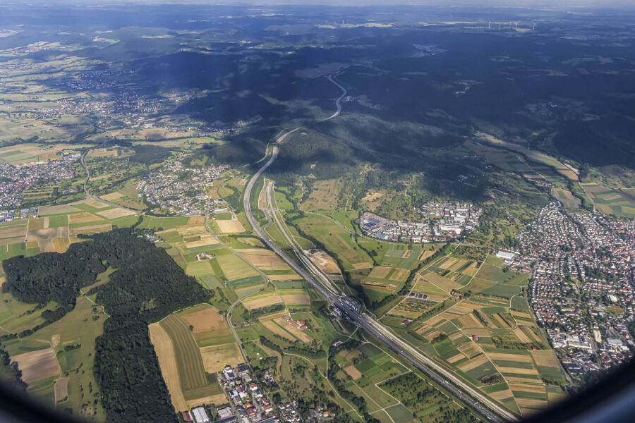Luftaufnahme einer Landschaft mit Feldern, Straßen und Siedlungen.