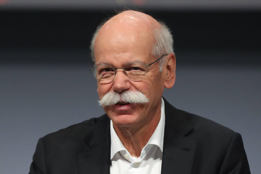 Älterer Mann mit Brille und weißem Schnurrbart, trägt Anzug und Hemd.