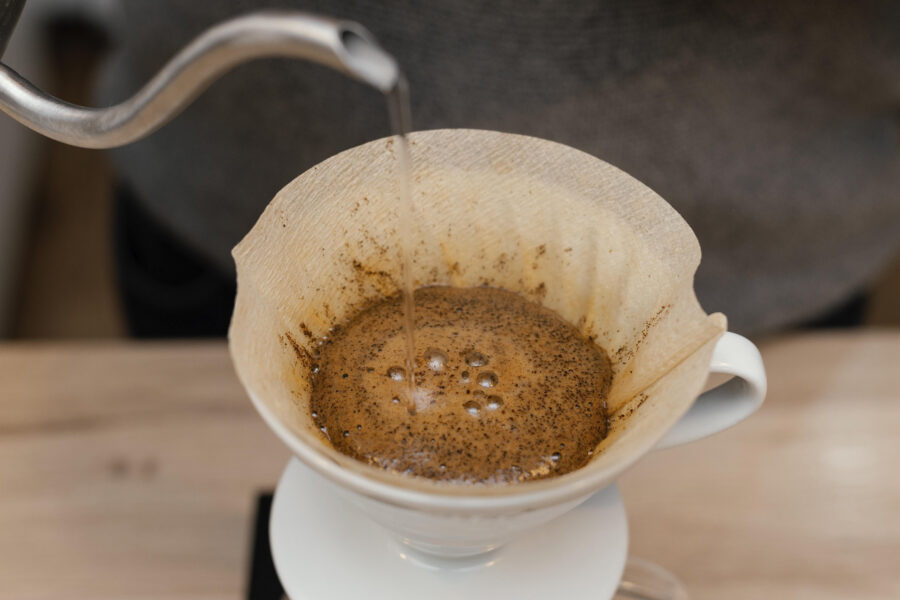 Wasser wird in einen Kaffeefilter mit Kaffeepulver gegossen.