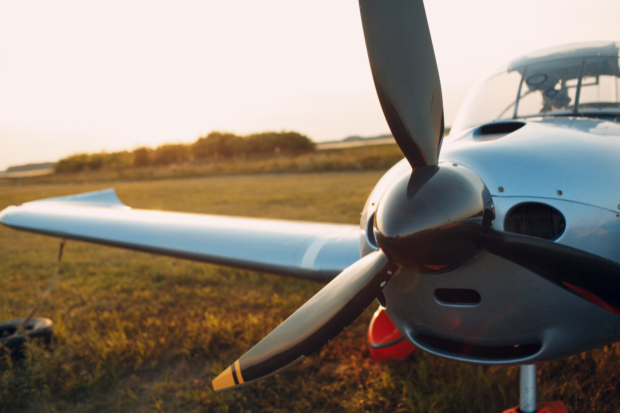 Propeller eines kleinen Flugzeugs auf Wiese bei Sonnenuntergang.