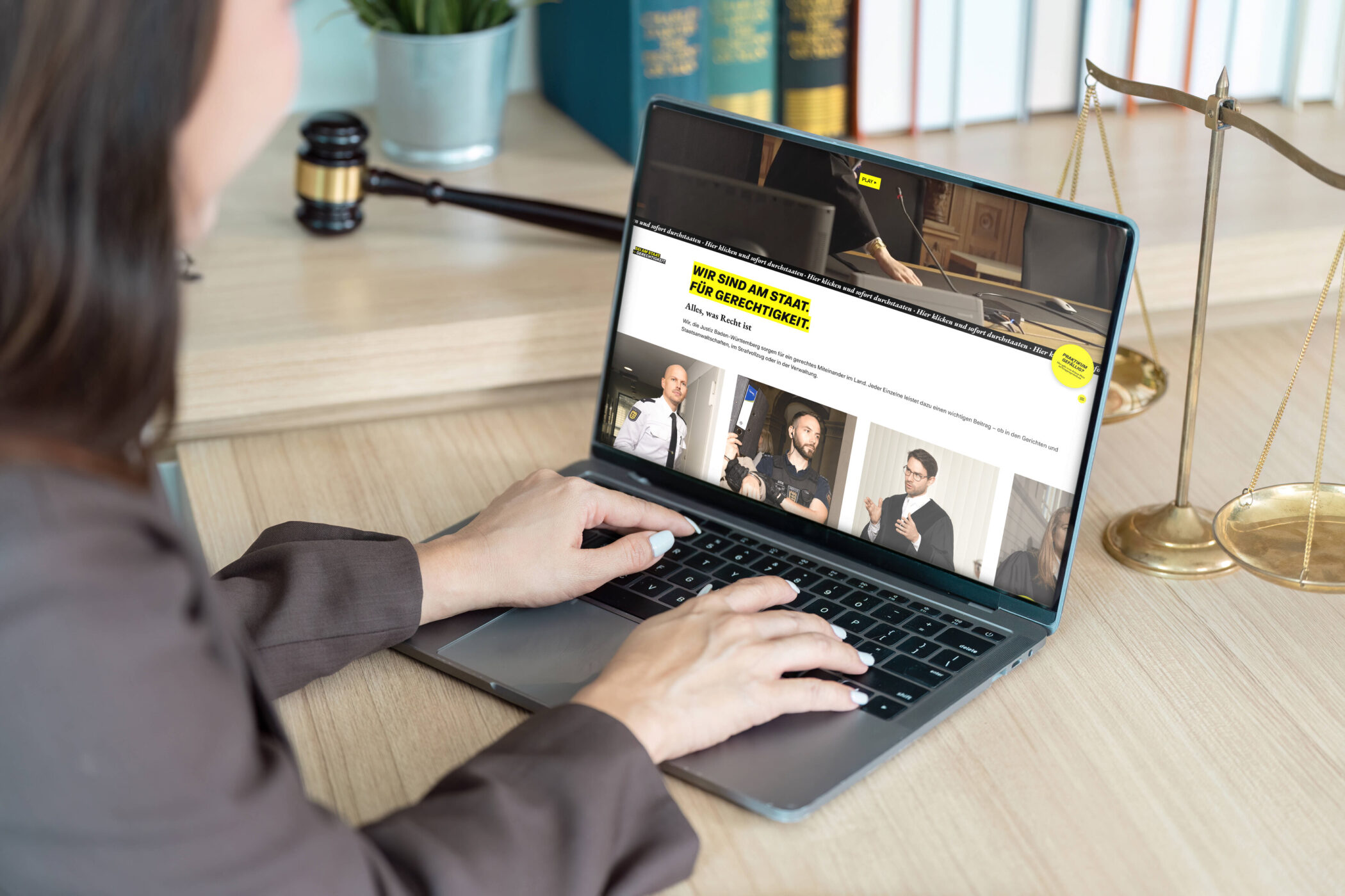 Person am Laptop bei einer Website über Gerechtigkeit, Waage und Hammer daneben.