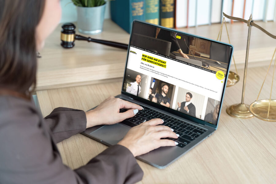 Person am Laptop bei einer Website über Gerechtigkeit, Waage und Hammer daneben.