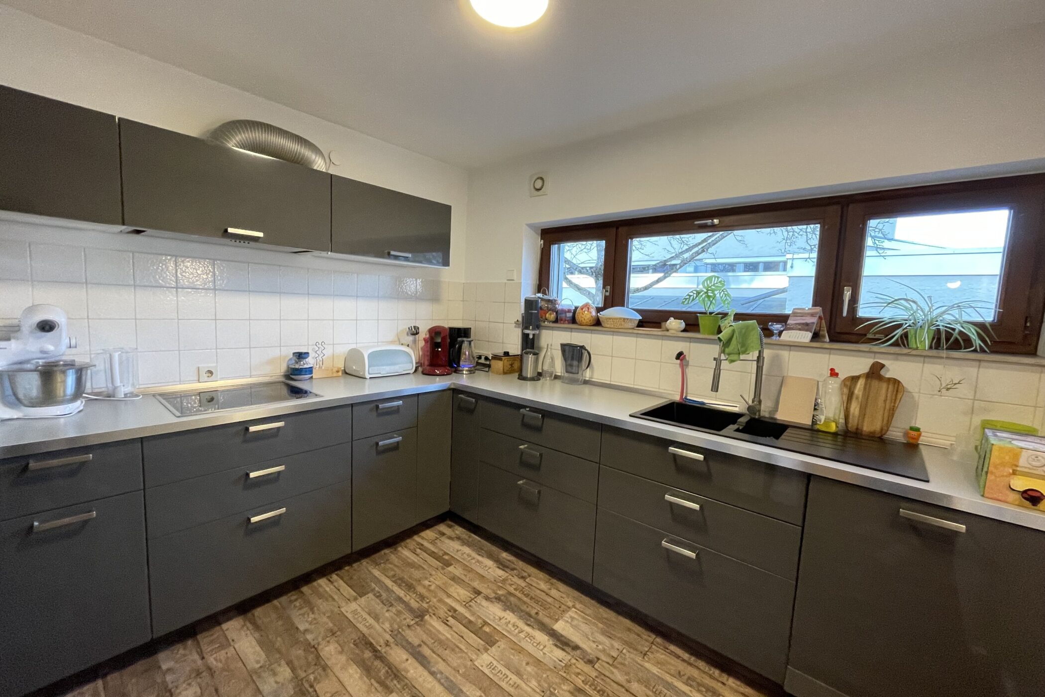 Moderne Küche mit dunklen Schränken, Fenster, Spüle und Küchengeräten.