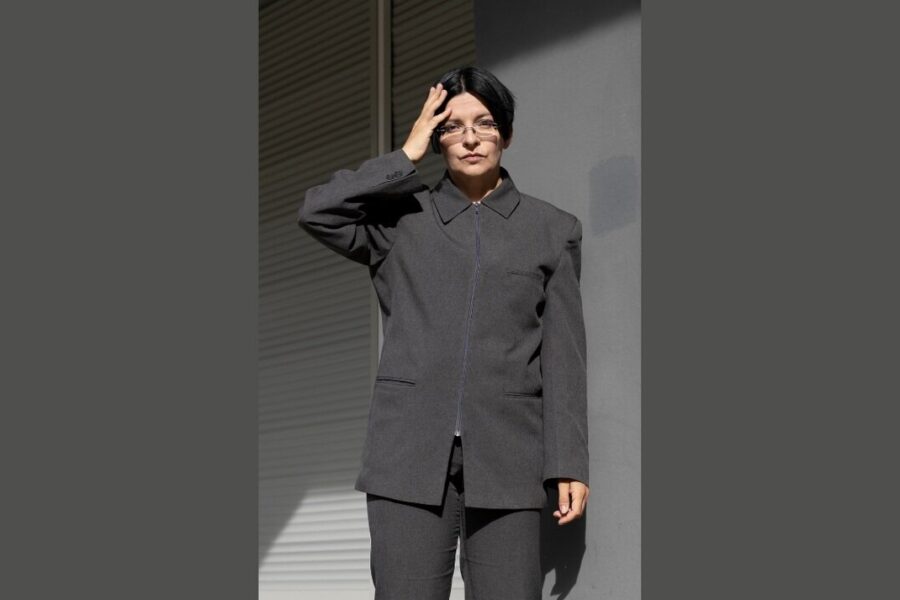 Eine Person in grauem Anzug berührt mit der Hand ihren Kopf.