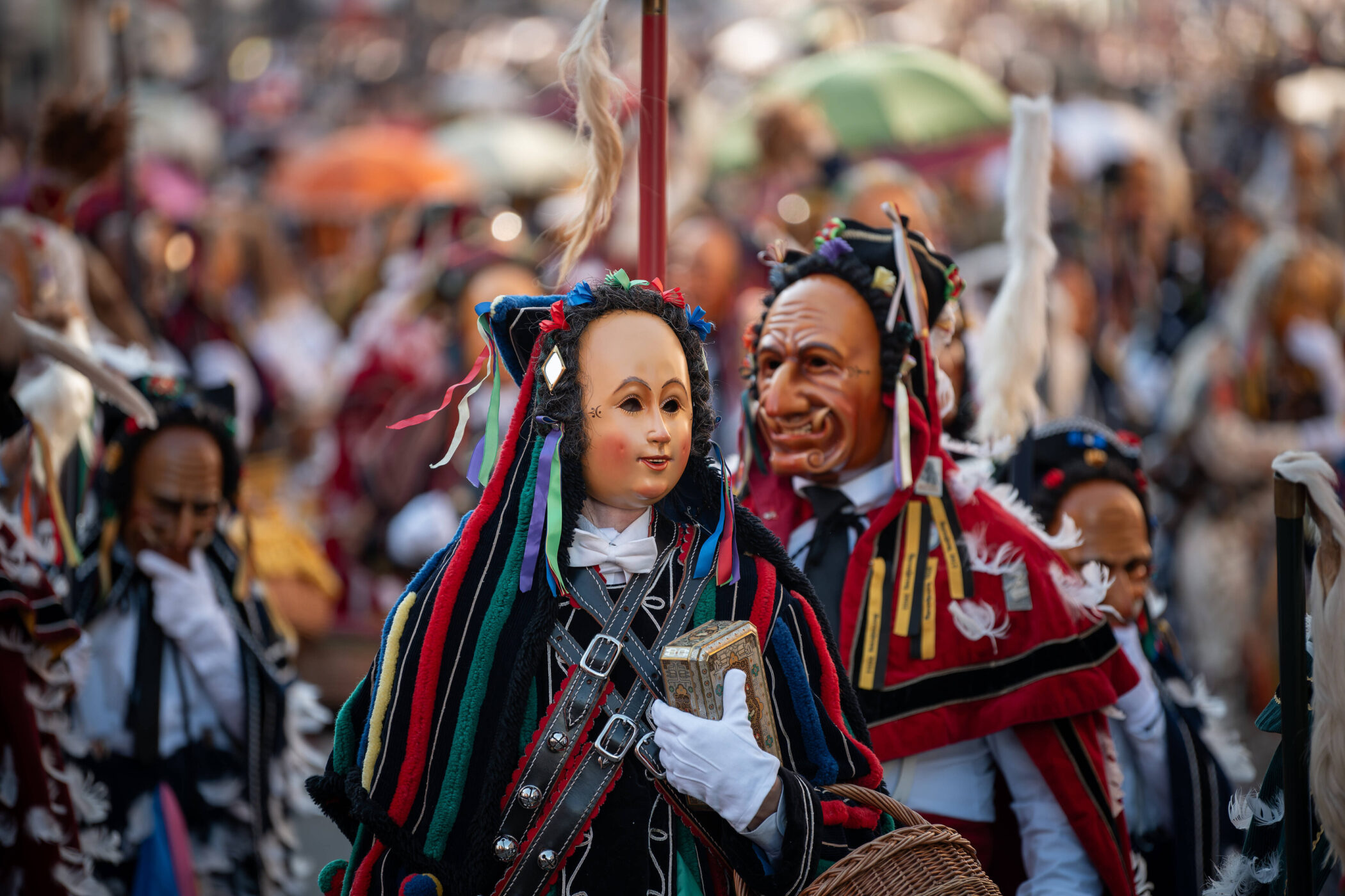 Menschen in bunten Kostümen und Masken bei einem Umzug.
